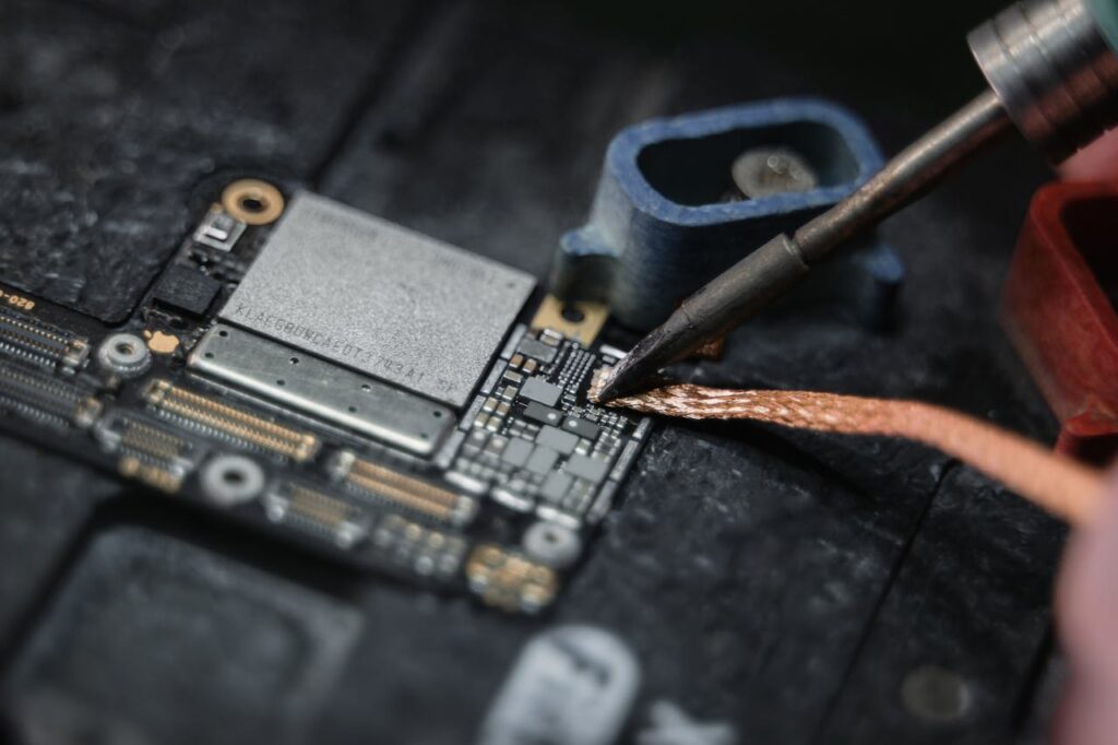 Detailed close-up of a soldering iron working on a circuit board, showcasing electronics repair.