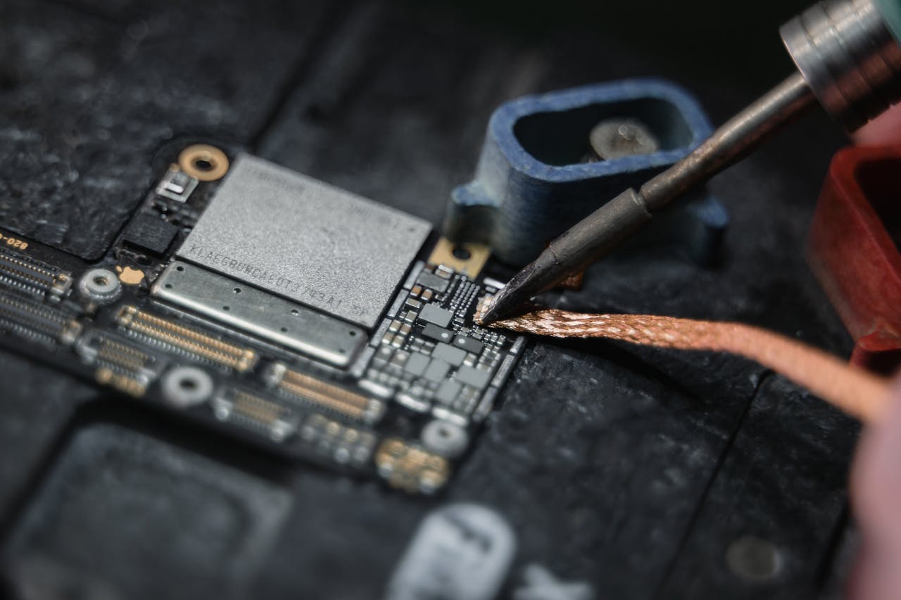 Detailed close-up of a soldering iron working on a circuit board, showcasing electronics repair.